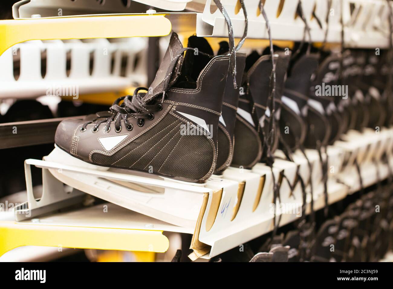 Rows of black ice skates, selective soft focus. Hire of winter sports equipment. Shelves with skates Stock Photo