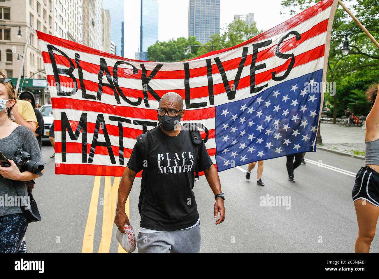 Demonstrator walks in front of an upside down American flag during the protest. Hundredths demonstrate in New York against President Trump's Fascist KKKAMPAIN and Black Lives Matter march on Juneteenth weekend. Demonstrators continue to march against police brutality and racial injustice across America. Stock Photo