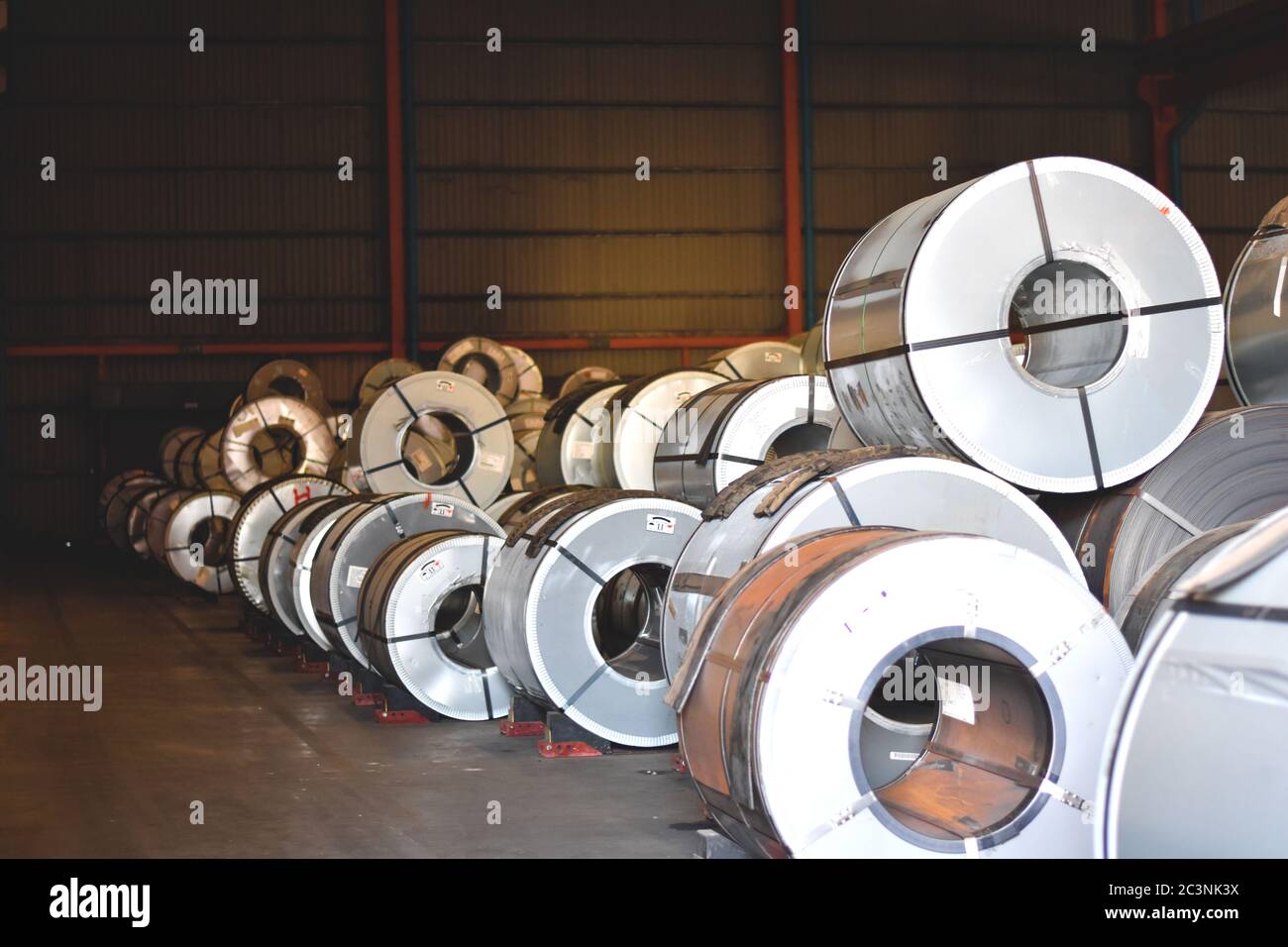 Steel coils on wooden pallets in warehouse stuffing area for container stuffing. Distribution warehouse and industrial raw material logistics. Stock Photo