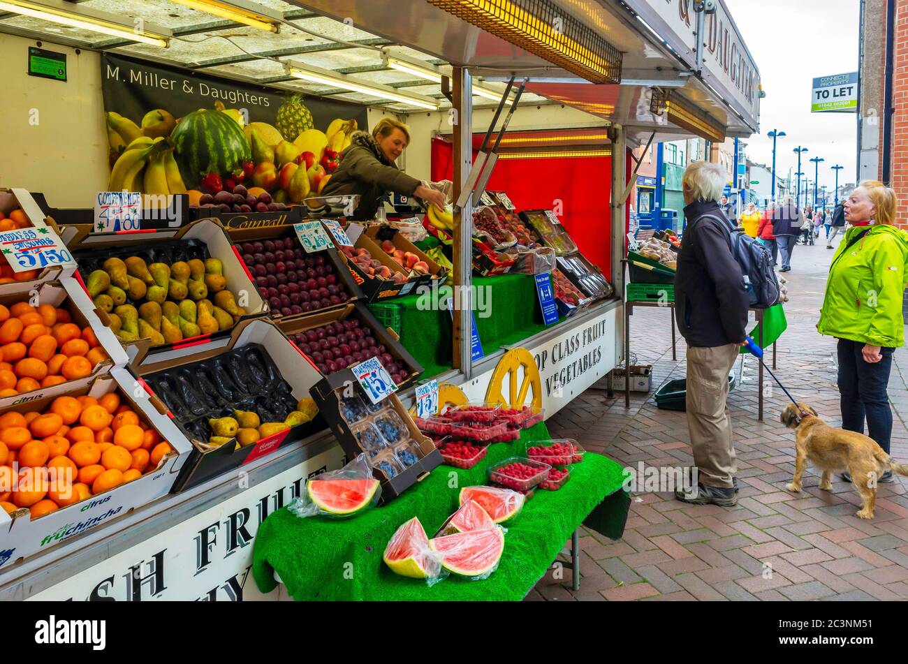 Elderly customers with a dog at a greengrocer and fruiterers market stall in Redcar Town Centre Stock Photo