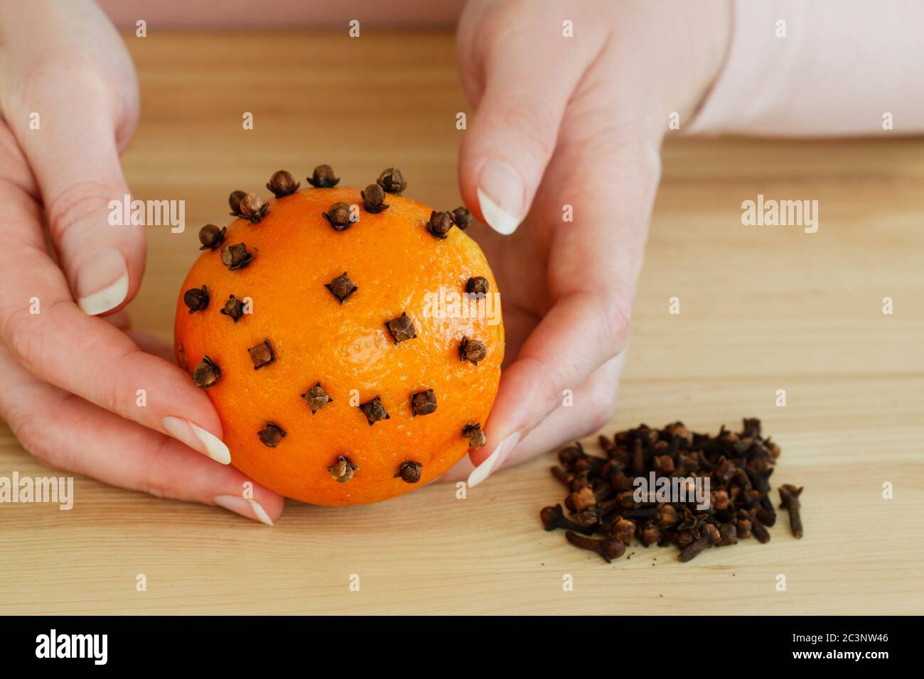 Woman shows how to make orange pomander ball with candle step by step