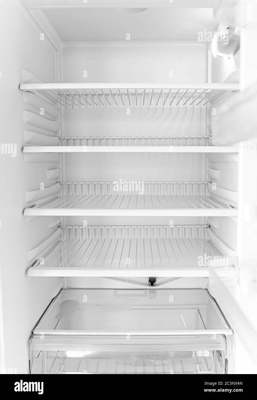 Defrosted refrigerator without food. Empty open white fridge. Stock Photo