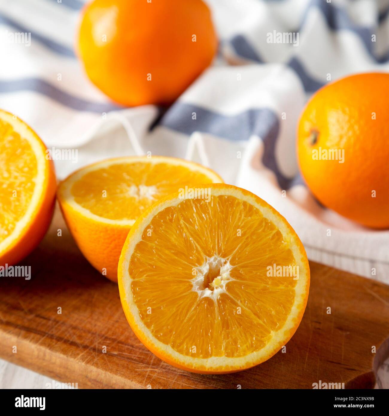 Halved and whole oranges on a rustic board, side view. Close-up. Stock Photo