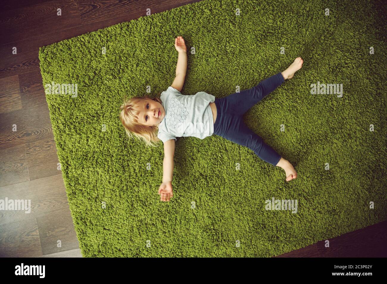 funny little girl lying on a carpet. child playing at home Stock Photo ...