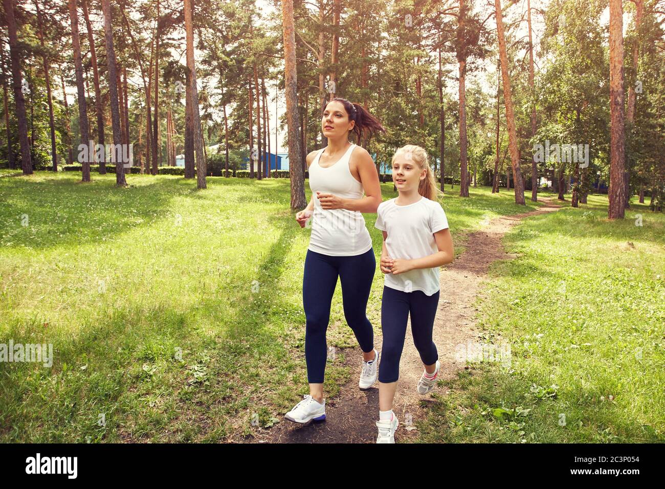 running sporty mother and daughter. woman and child jogging in a park ...