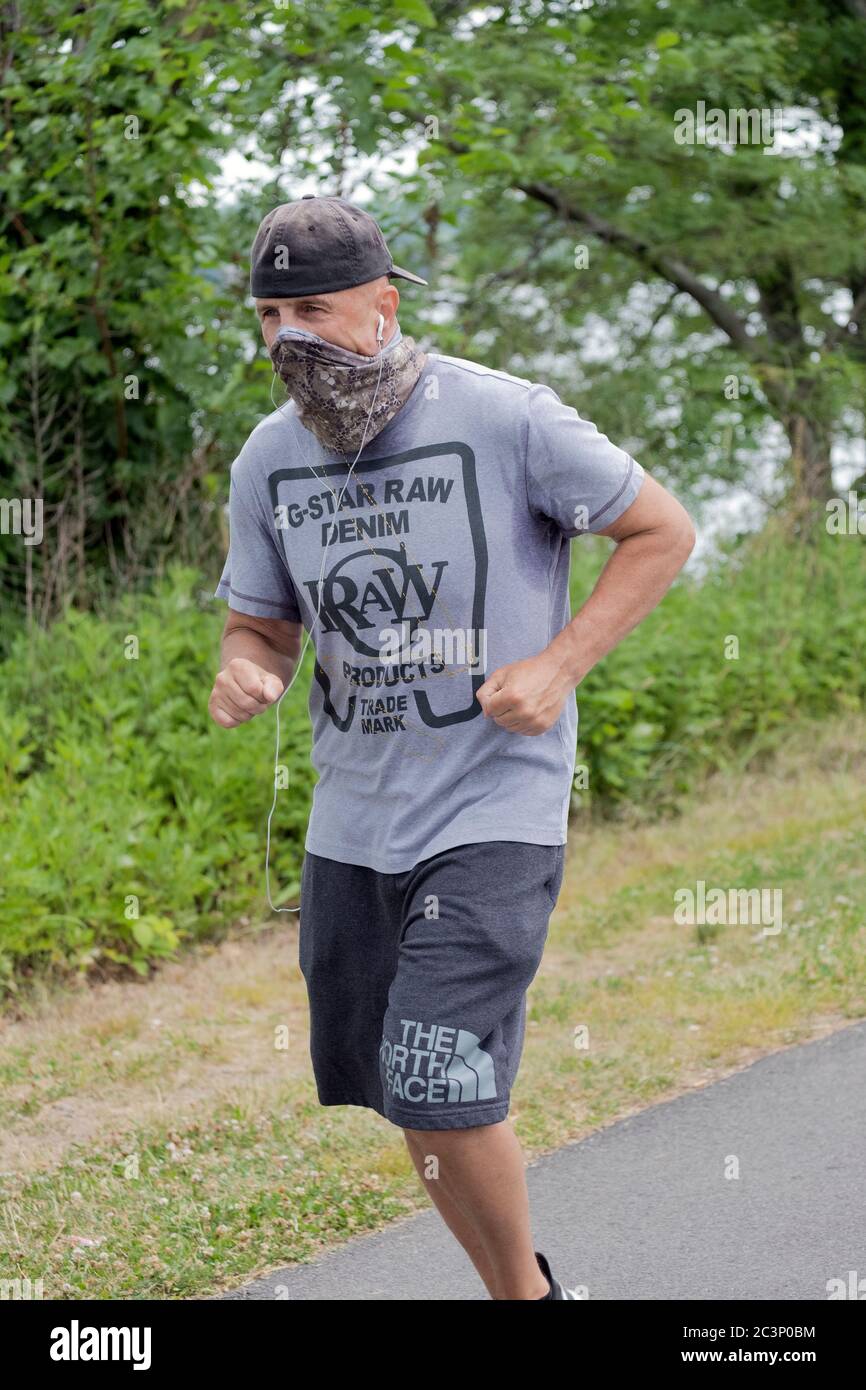 A man running with a bandana face covering. On a path near the Bayside Maina in Queens, New York City. Stock Photo