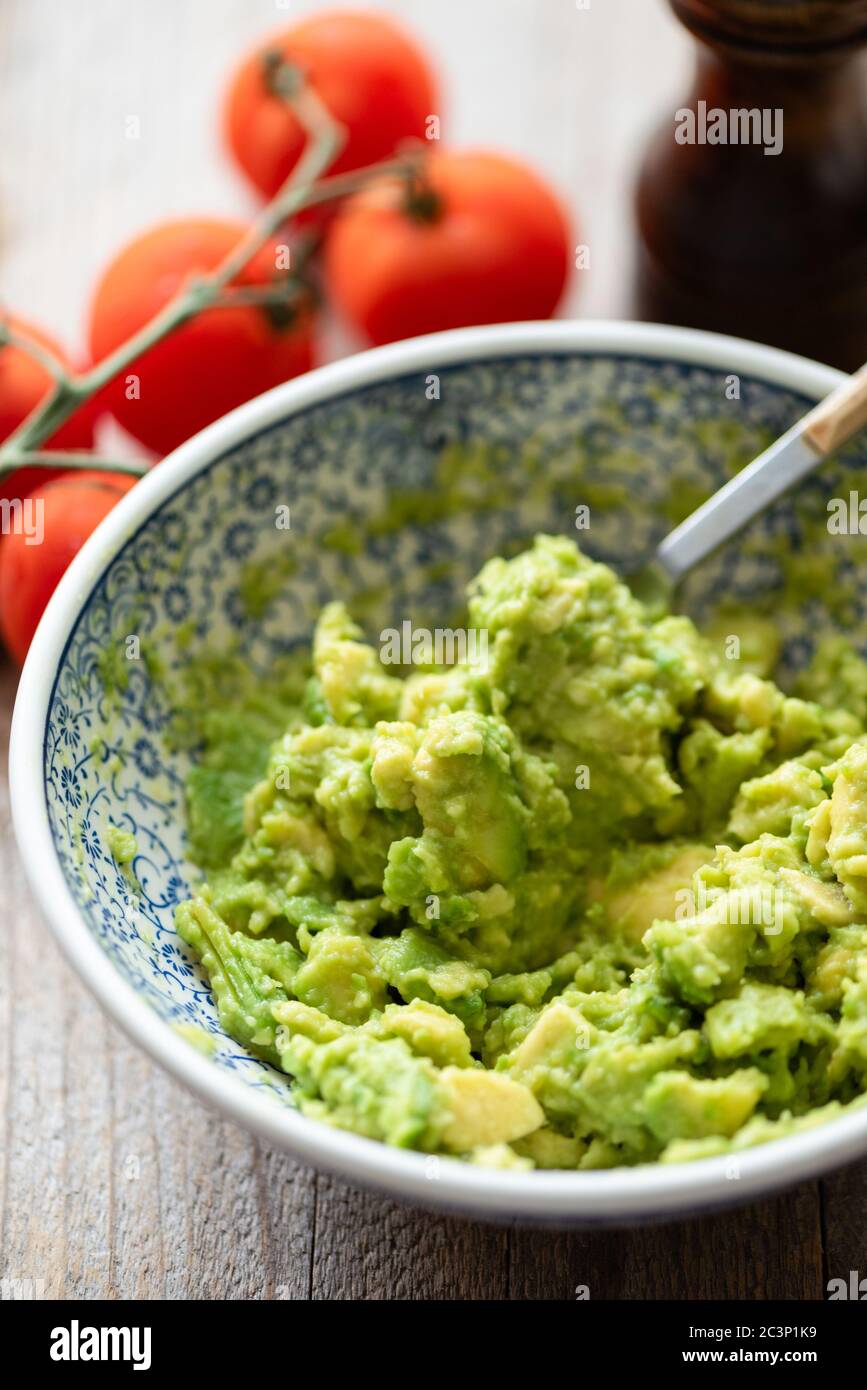 Mashed avocado in bowl. Chunky guacamole sauce Stock Photo