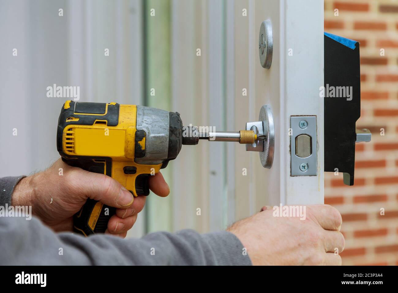 Handyman using a screwdriver drill to installing lock in door in a