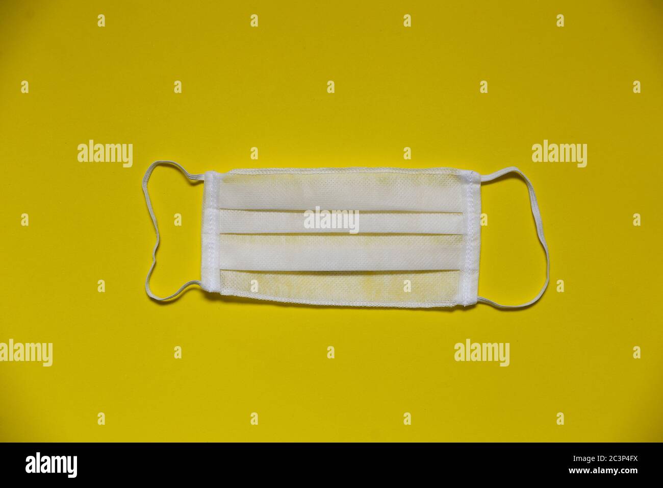 White protective facial respiratory mask on yellow background Stock Photo