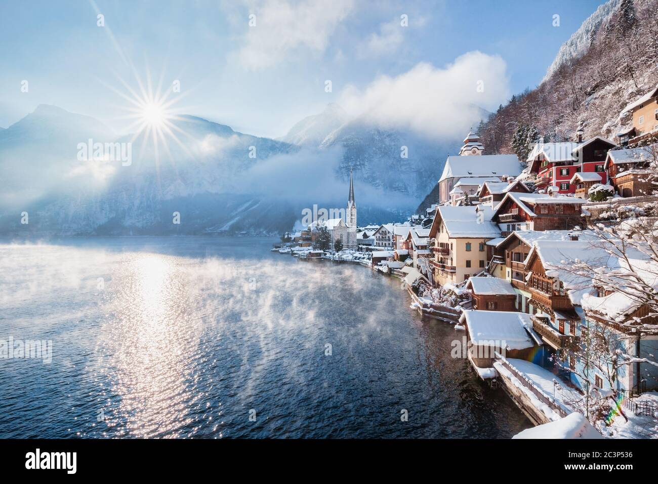 Classic postcard view of famous Hallstatt lakeside town in the Alps with the sun rising above mountain peaks on a frosty morning in winter, Salzkammer Stock Photo
