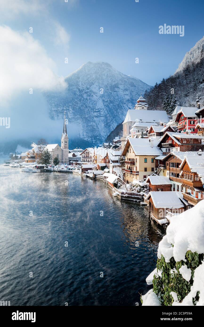 Classic postcard view of famous Hallstatt lakeside town in the Alps with passenger ship on a beautiful cold sunny day with blue sky and clouds in wint Stock Photo