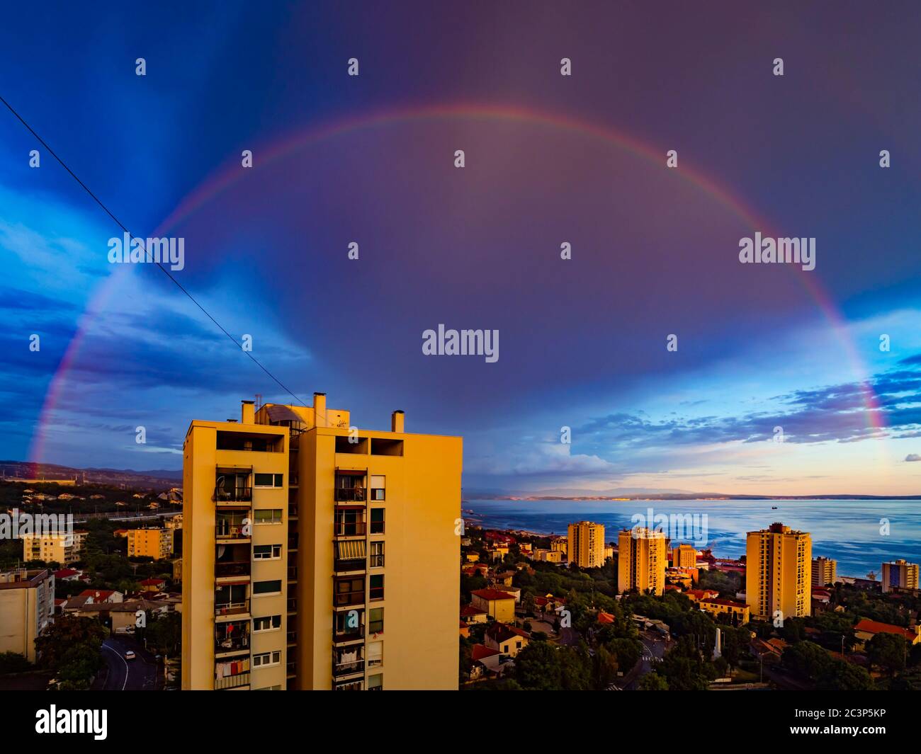 Evening full arc arch rainbow above skyscraper house building Stock Photo