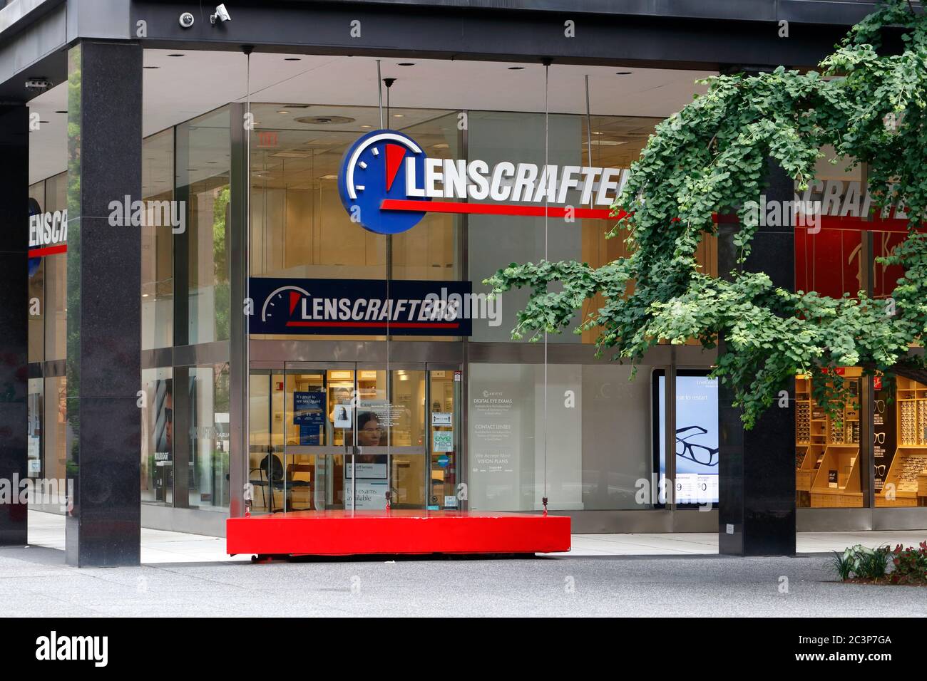 LensCrafters, 777 Third Ave, New York, NY. exterior storefront of an eye care center and a Big Red Swing sculpture by Theodore Ceraldi in Manhattan. Stock Photo