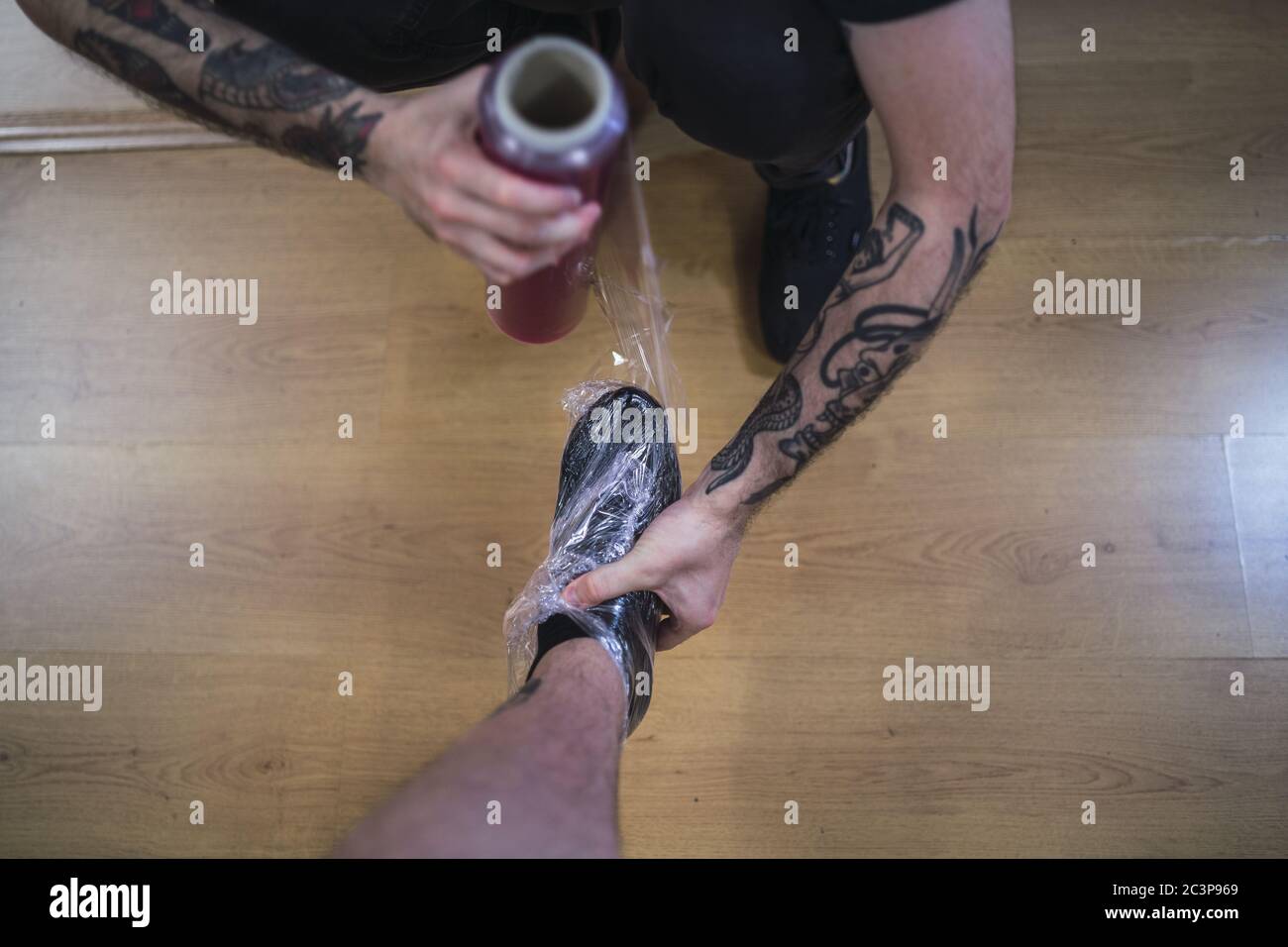 High angle shot of a tattoo artist wrapping the client's foot in plastic wrap Stock Photo