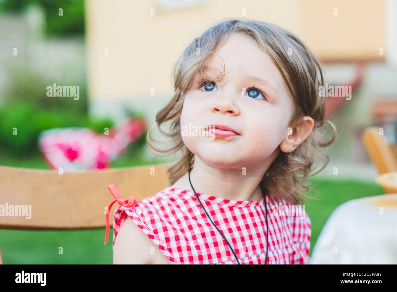 Girl Eating Sausage At Family Barbeque. 2 years old girl eats sausage
