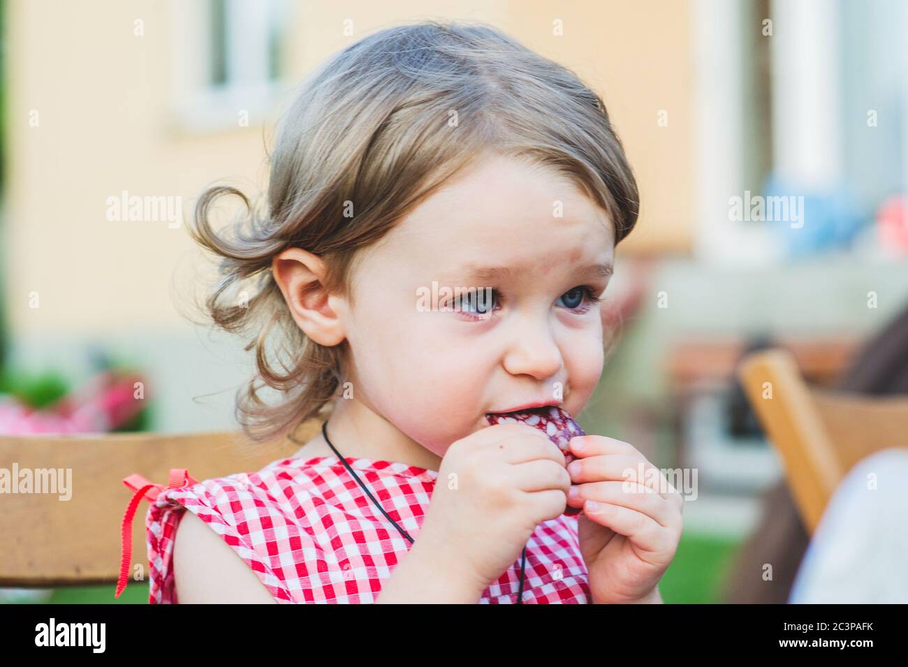 Girl Eating Sausage At Family Barbeque. 2 years old girl eats sausage