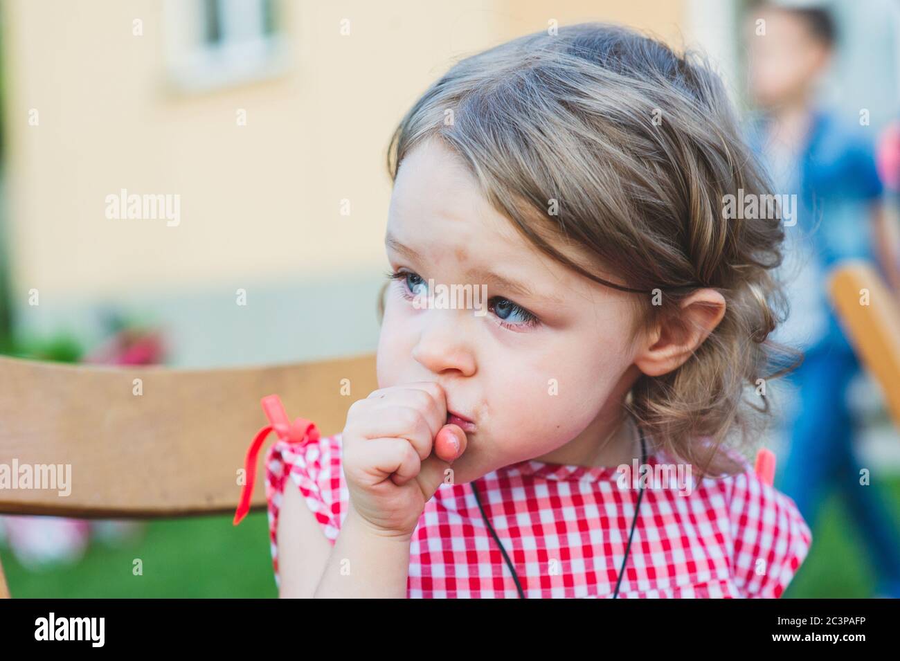 Girl Eating Sausage At Family Barbeque. 2 years old girl eats sausage
