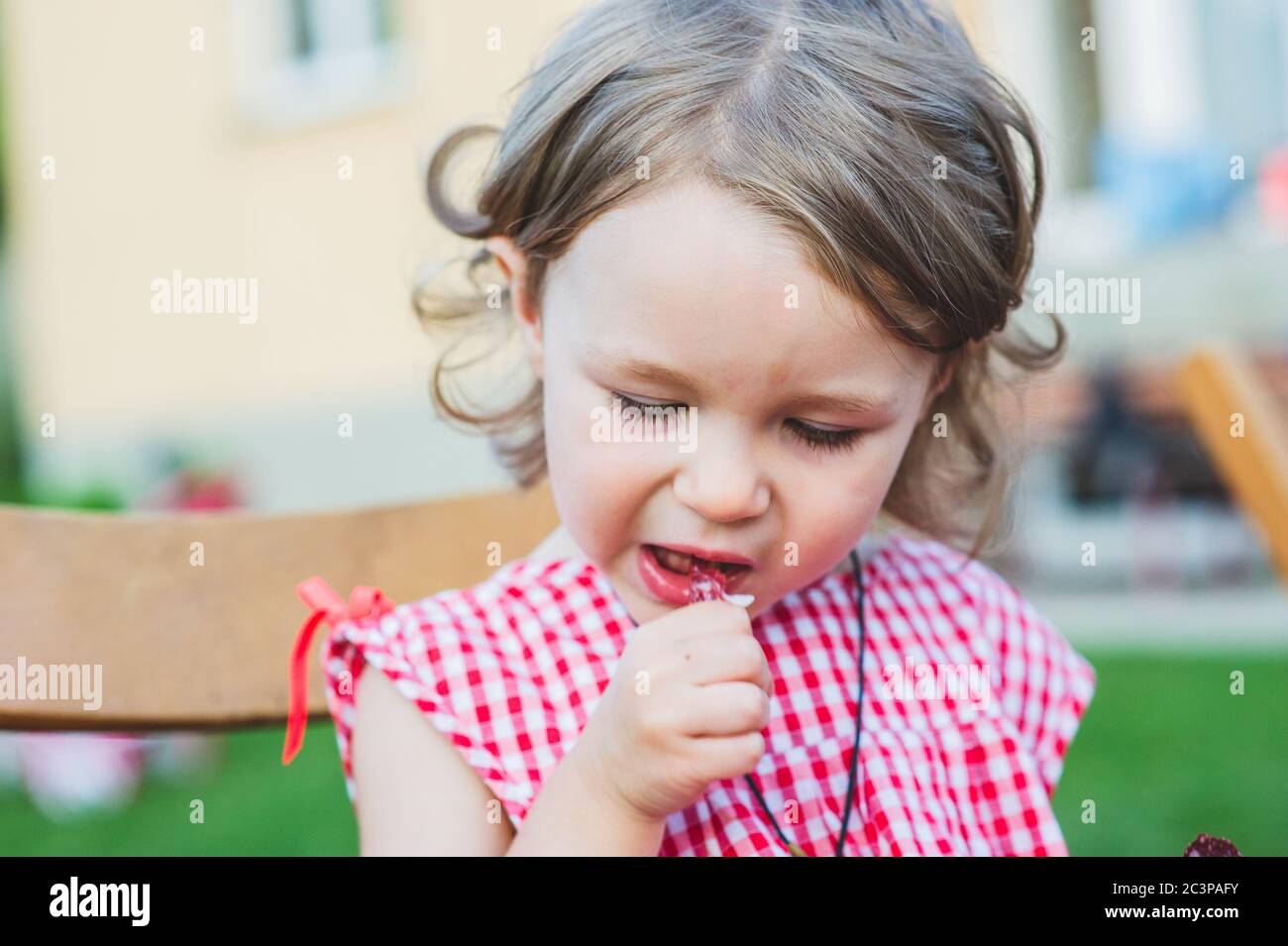 Girl Eating Sausage At Family Barbeque. 2 years old girl eats sausage