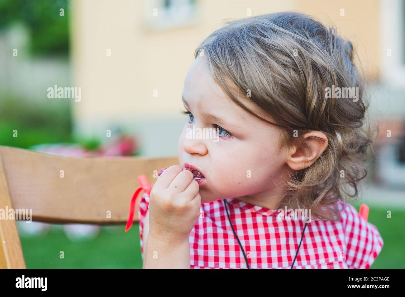Girl Eating Sausage At Family Barbeque. 2 years old girl eats sausage