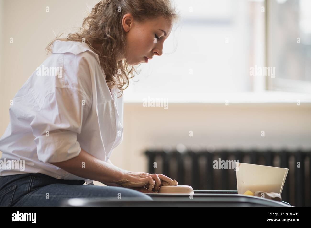 Potter makes the clay product with pottery modeling tools on the potter's wheel. Stock Photo