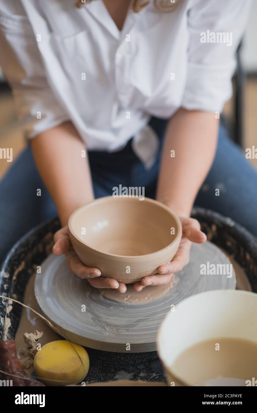 The female potter finished making a clay vase remove it from the potter