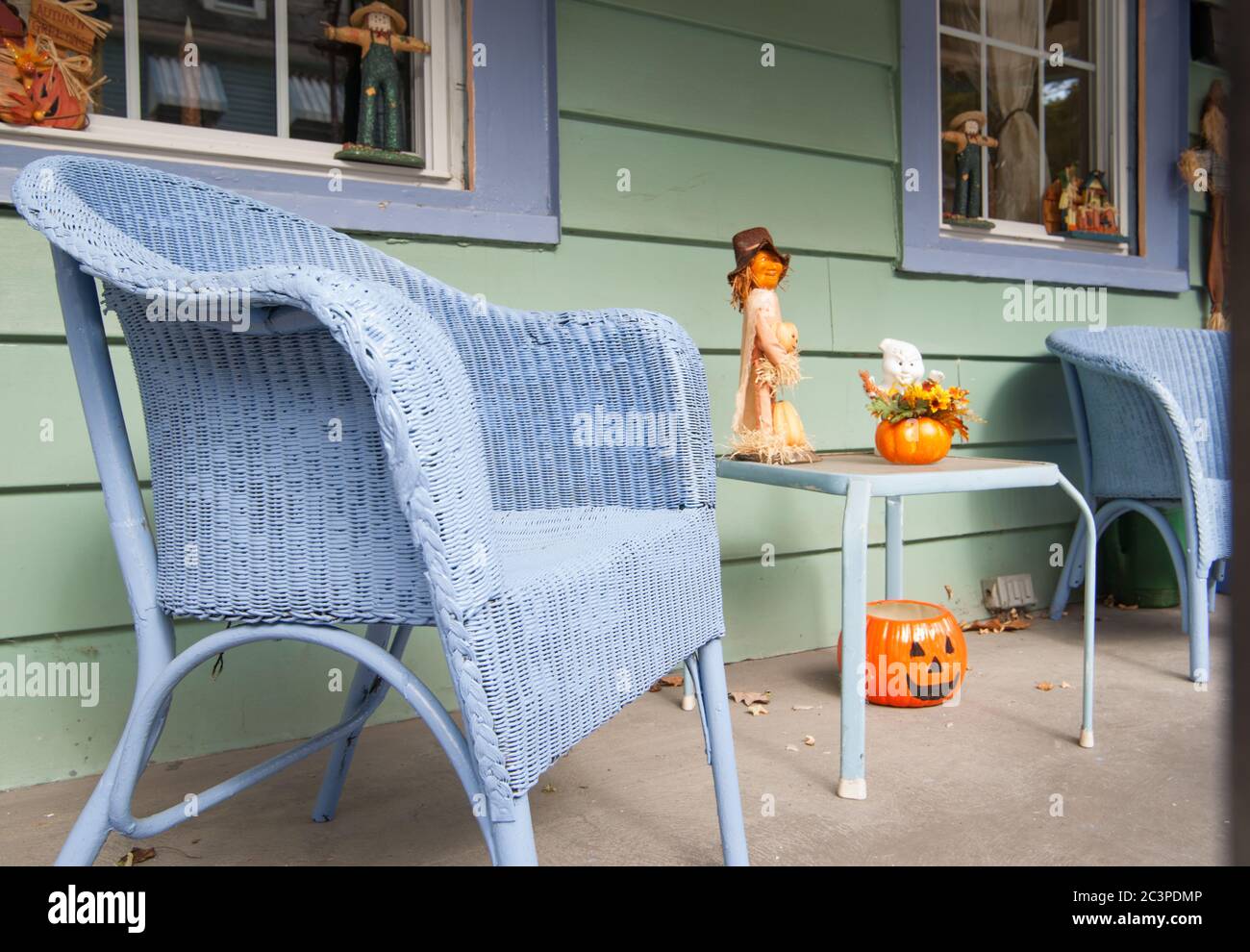 quaint front porch on street with blue wicker chairs and halloween