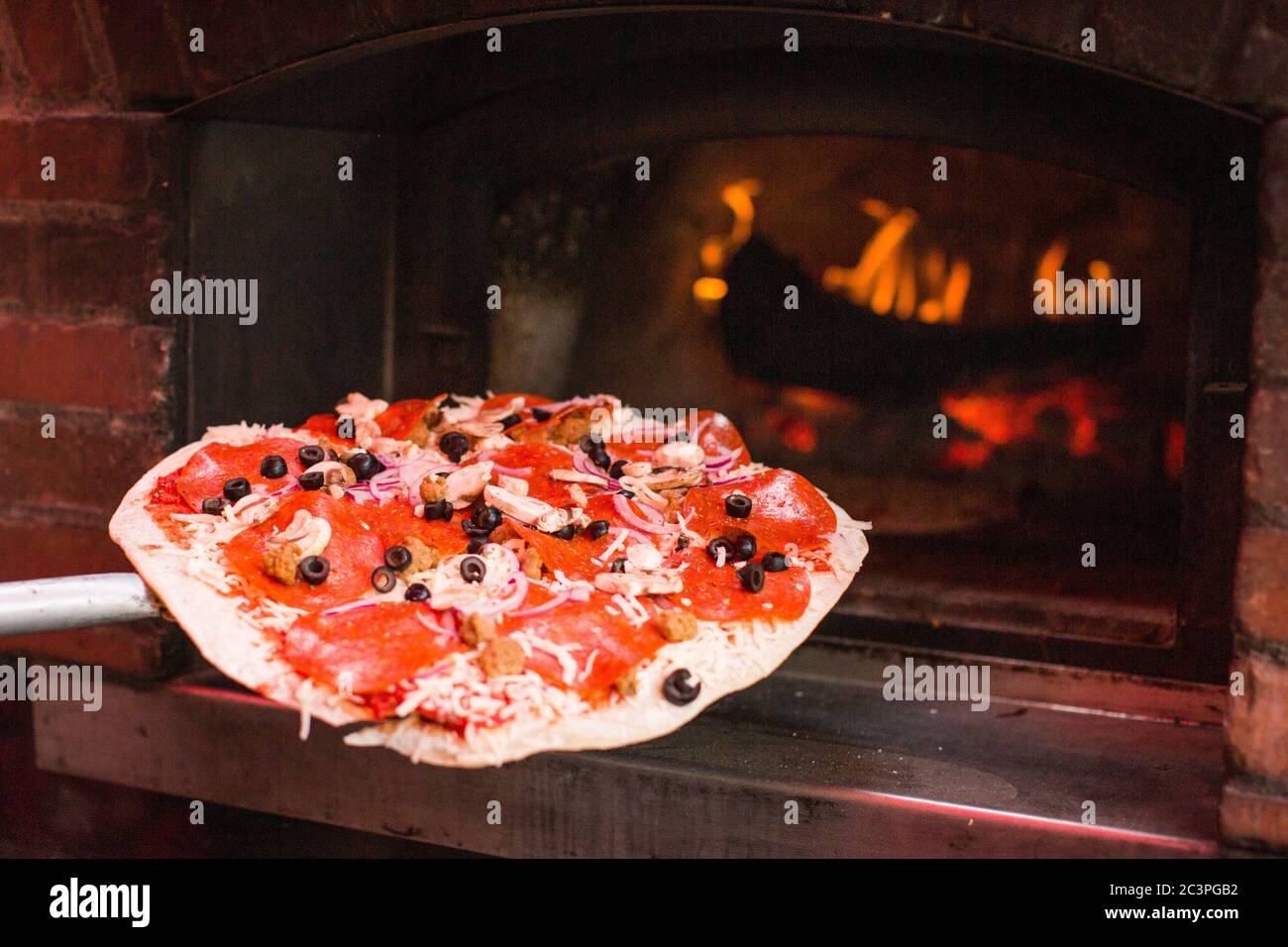 Closeup shot of a person putting a pizza in a fireplace - perfect for food concepts Stock Photo
