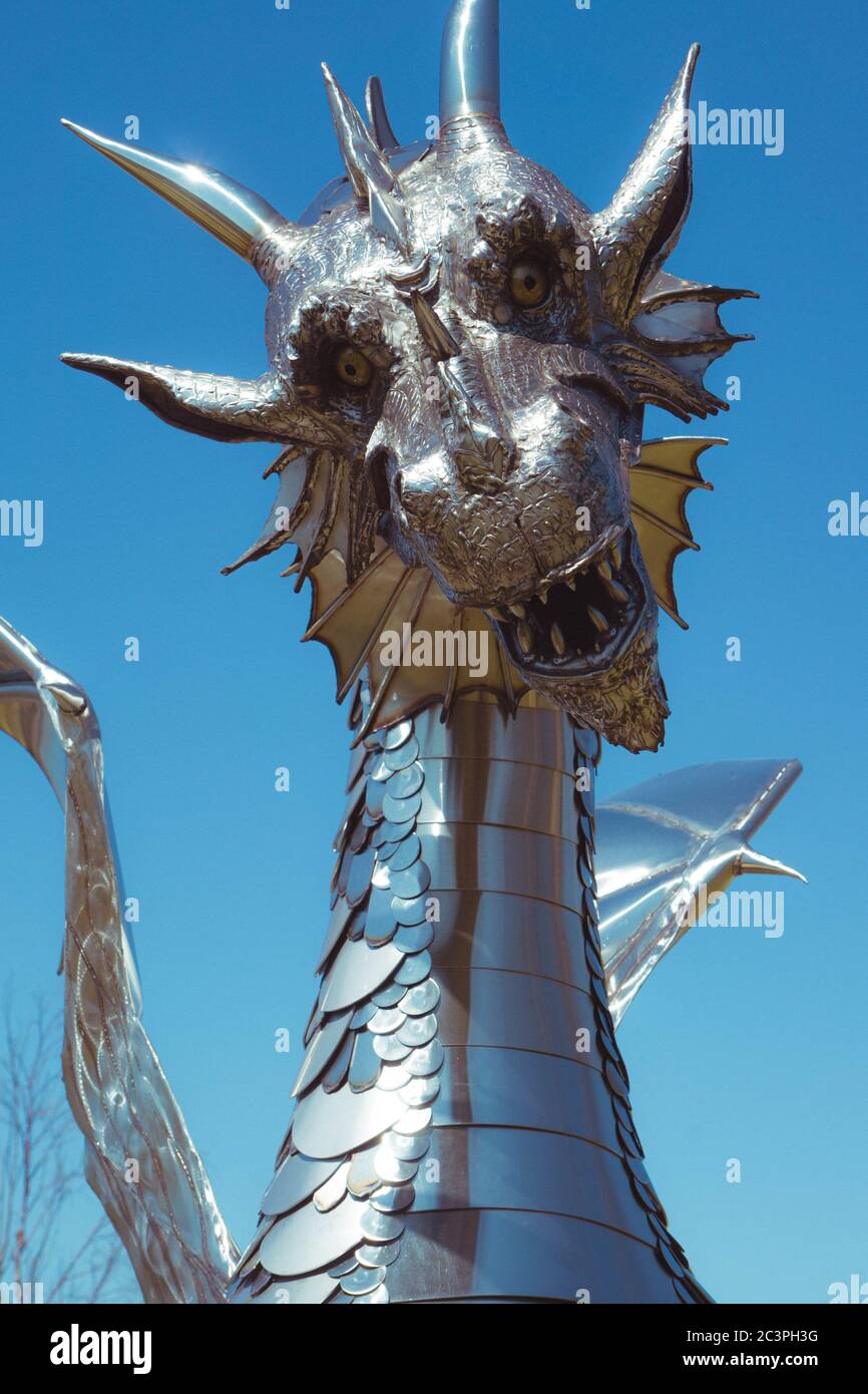 Vertical low angle shot of the metal statue of a dragon captured under the blue sky Stock Photo