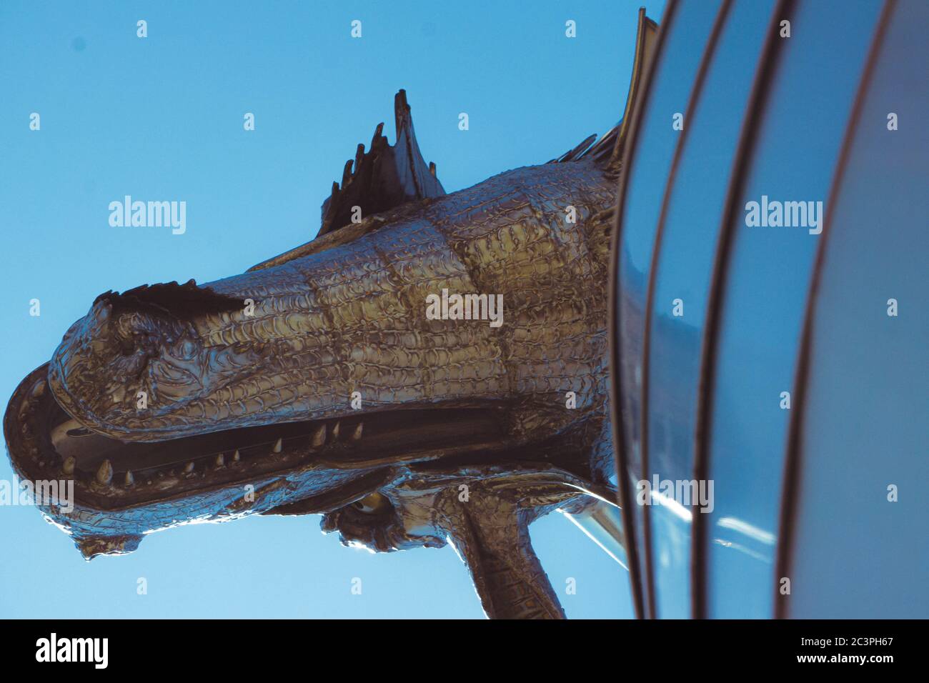 Low angle shot of the metal statue of a dragon captured under the blue sky Stock Photo