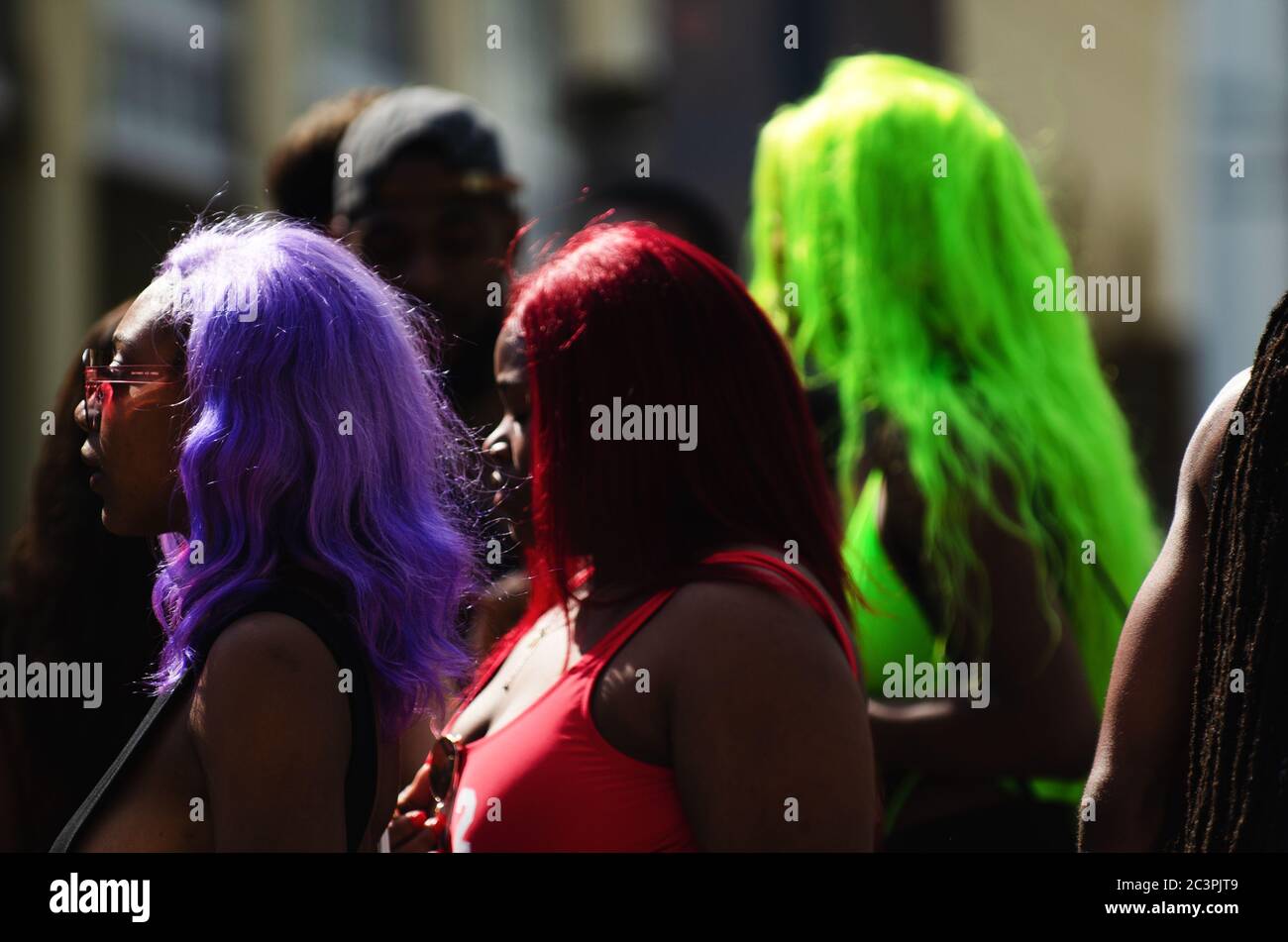 MIAMI - MARCH 17, 2019: Young women with brightly colored hair walk through a gathering of college students celebrating spring break on Ocean Drive. Stock Photo