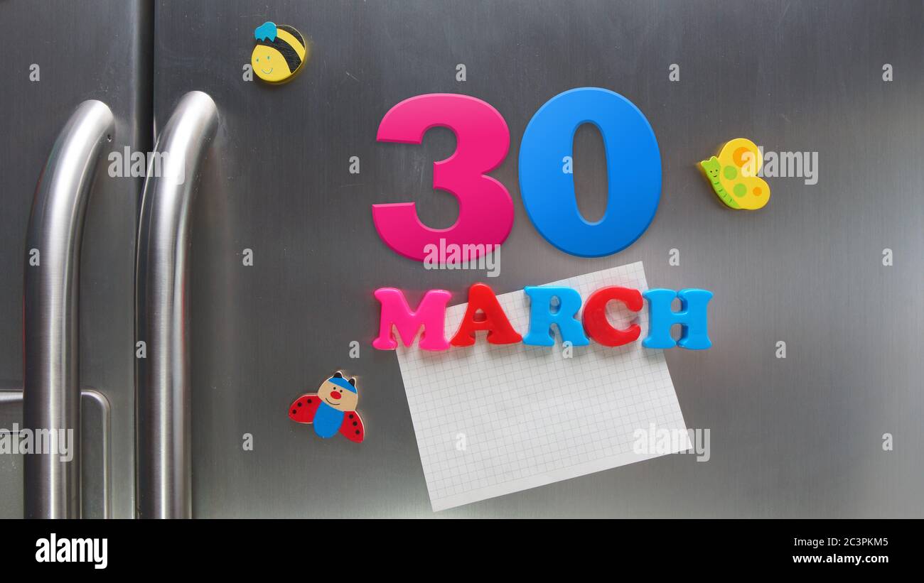 March 30 calendar date made with plastic magnetic letters holding a note of graph paper on door refrigerator Stock Photo