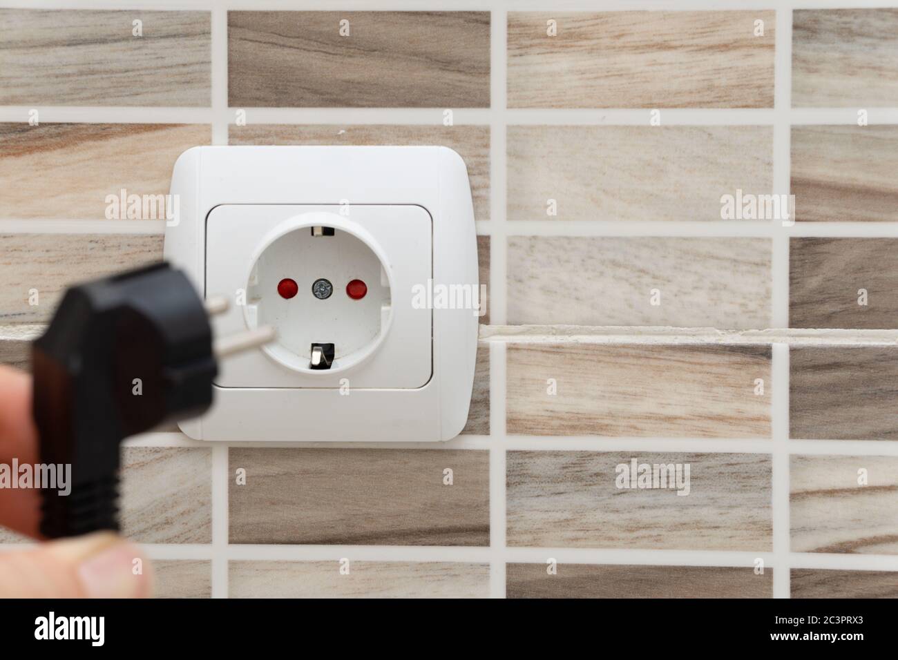 Installing plug into the electrical outlet on the wall Stock Photo Alamy