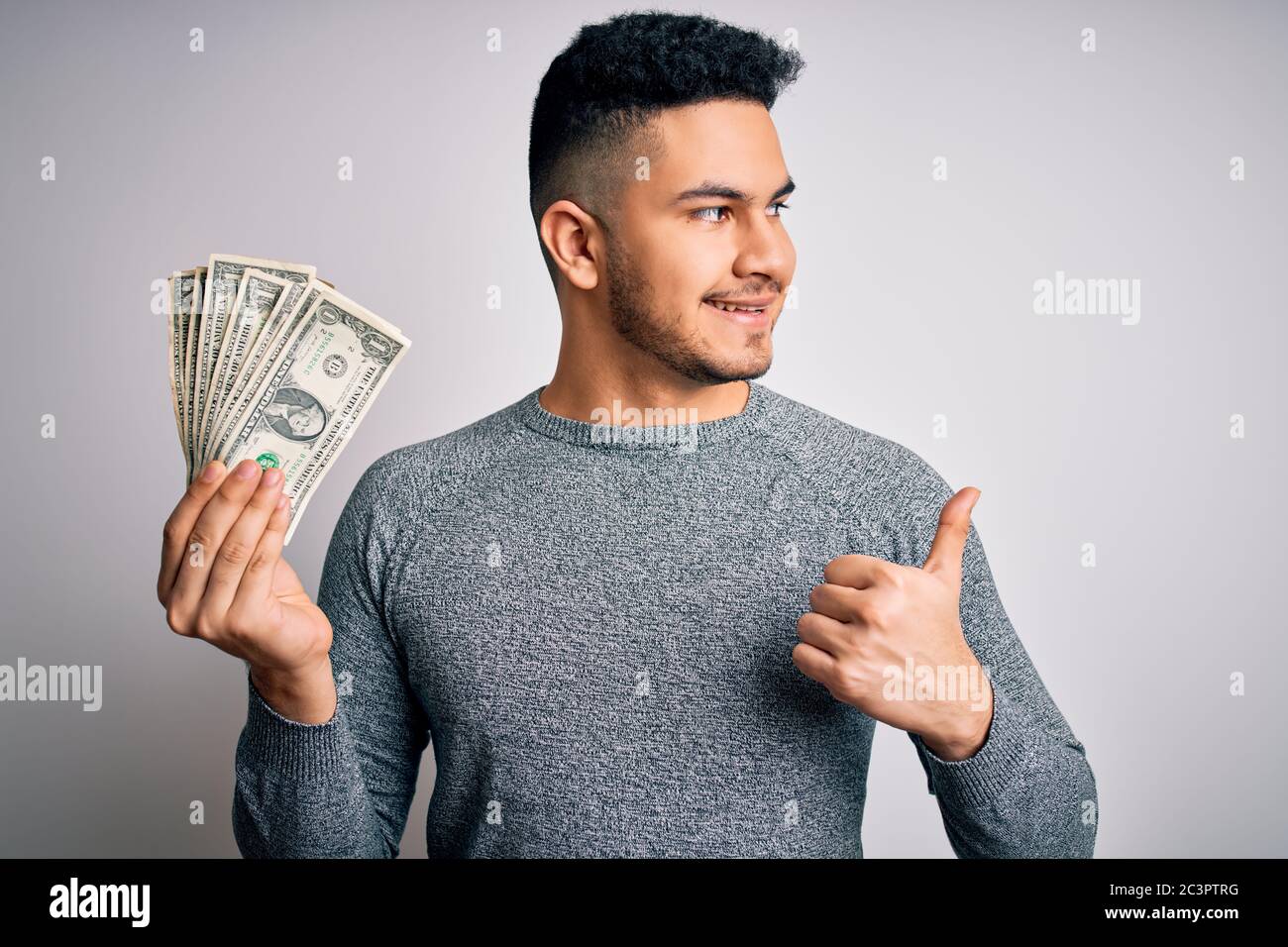 Young handsome man holding bunch of dollars banknotes over isolated ...