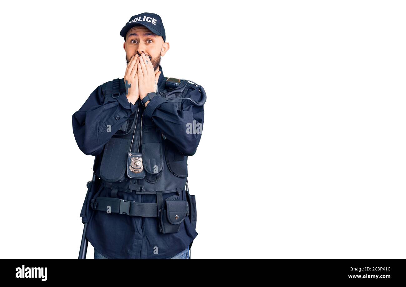 Young handsome man wearing police uniform laughing and embarrassed giggle covering mouth with hands, gossip and scandal concept Stock Photo