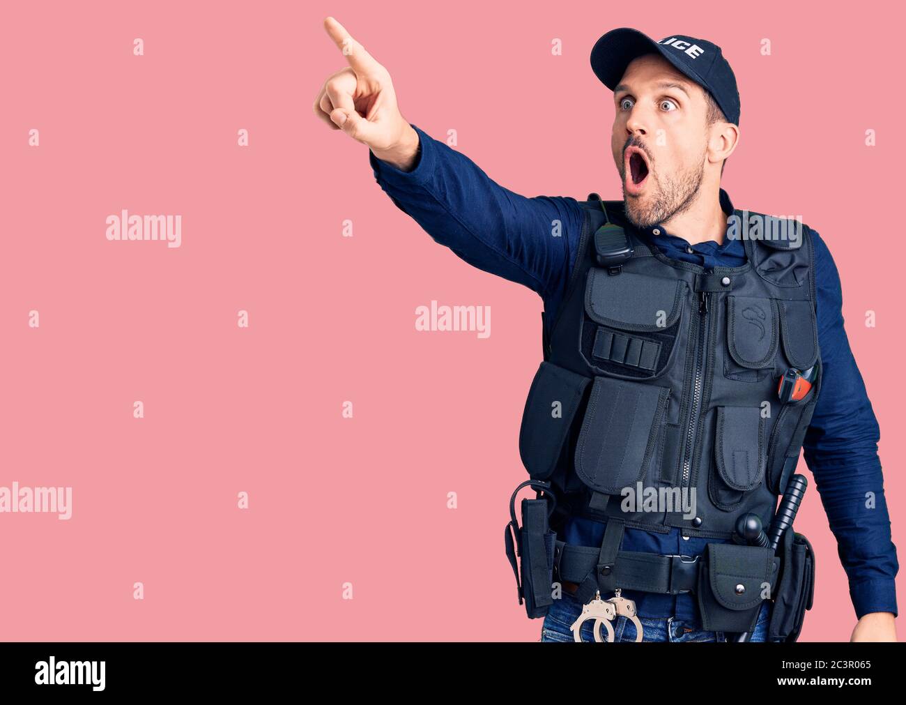 Young handsome man wearing police uniform pointing with finger ...
