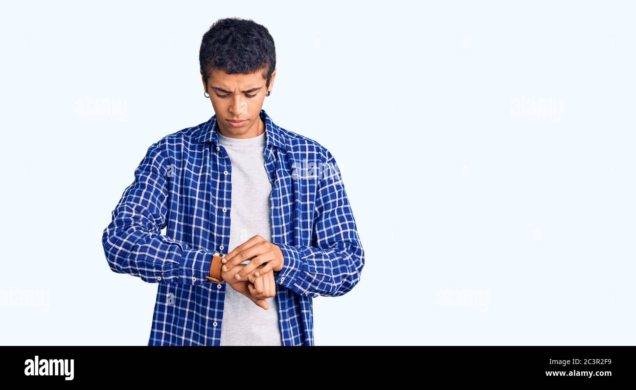 Young african amercian man wearing casual clothes checking the time on ...