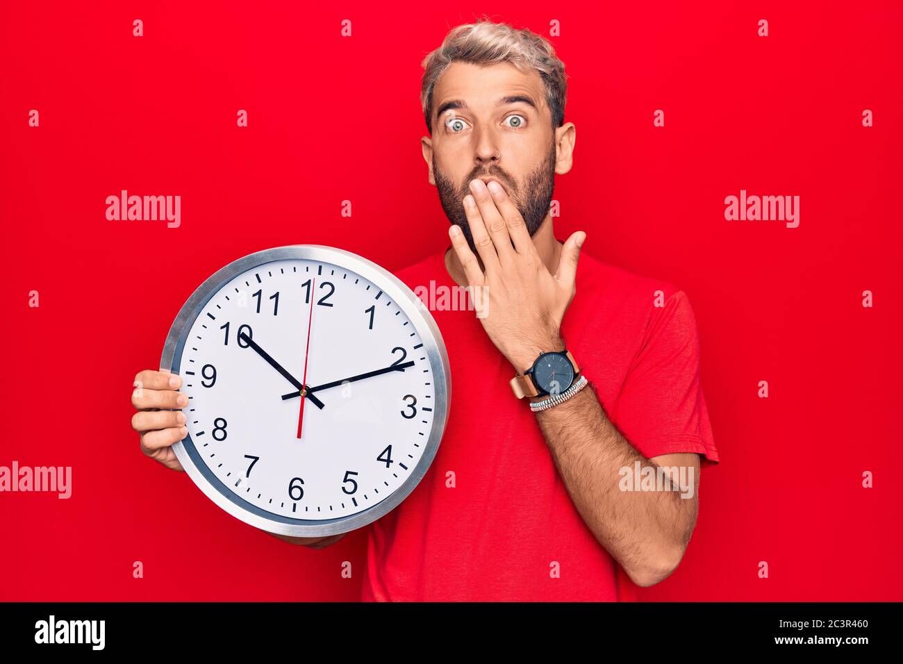 Young handsome blond man with beard doing countdown using big clock ...