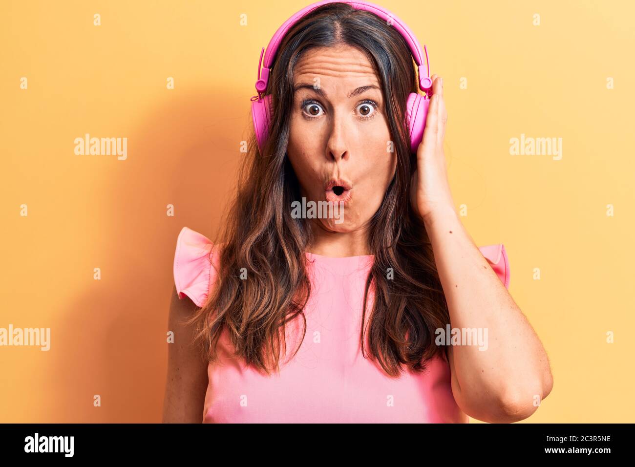 Young beautiful brunette woman listening to music using headphones over ...