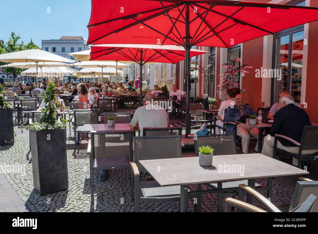 Wismar, Germany, June 15, 2020: People are enjoying the sunny summer day in a street cafe onthe market place after lock down during the coronavirus pa Stock Photo