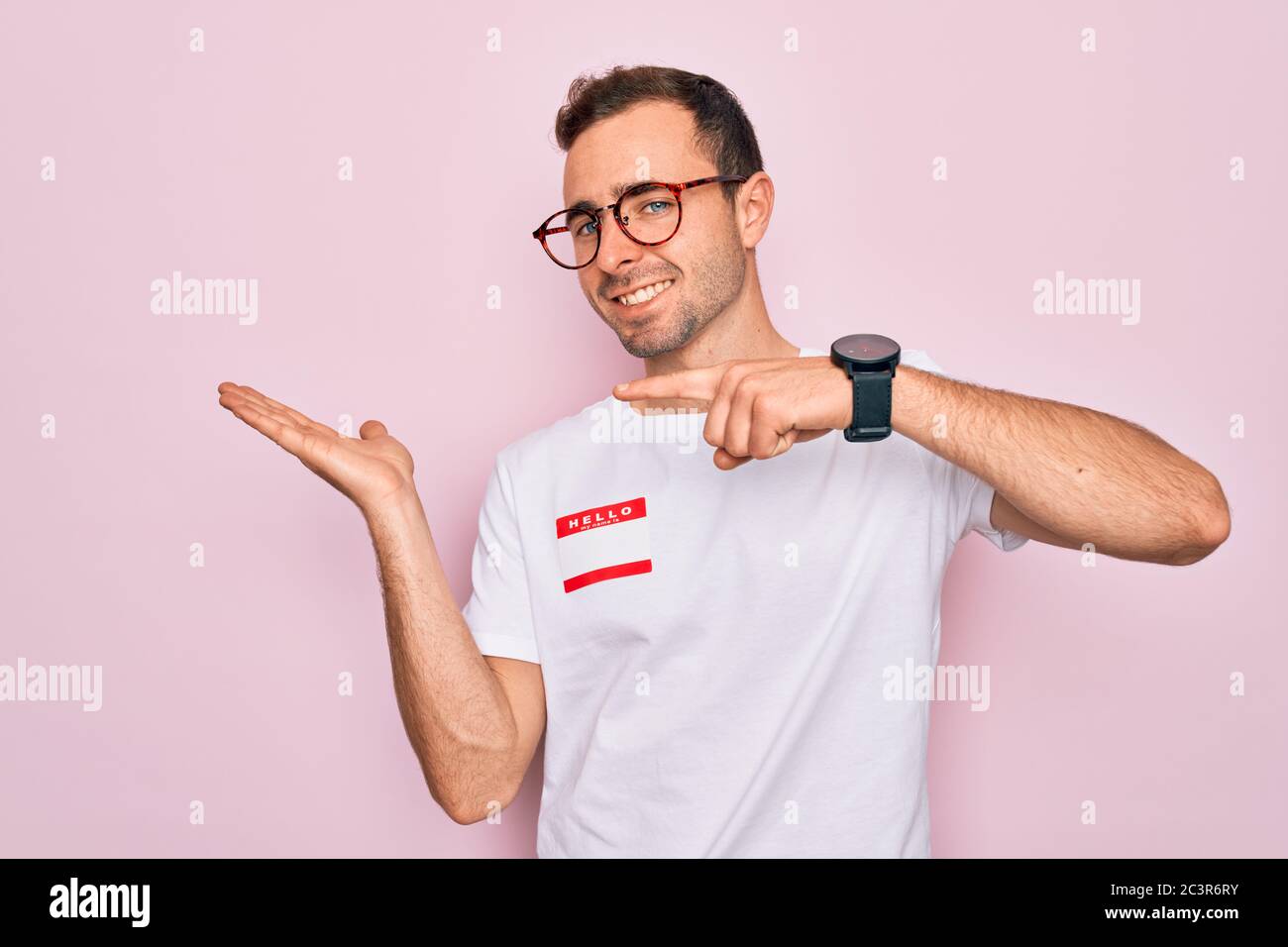 Handsome man with blue eyes wearing sticker with hello my name is ...
