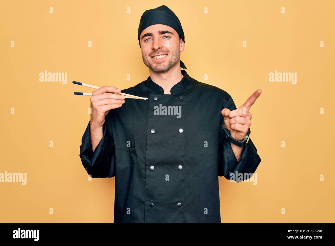Young handsome cooker man with blue eyes wearing uniform and hat using ...