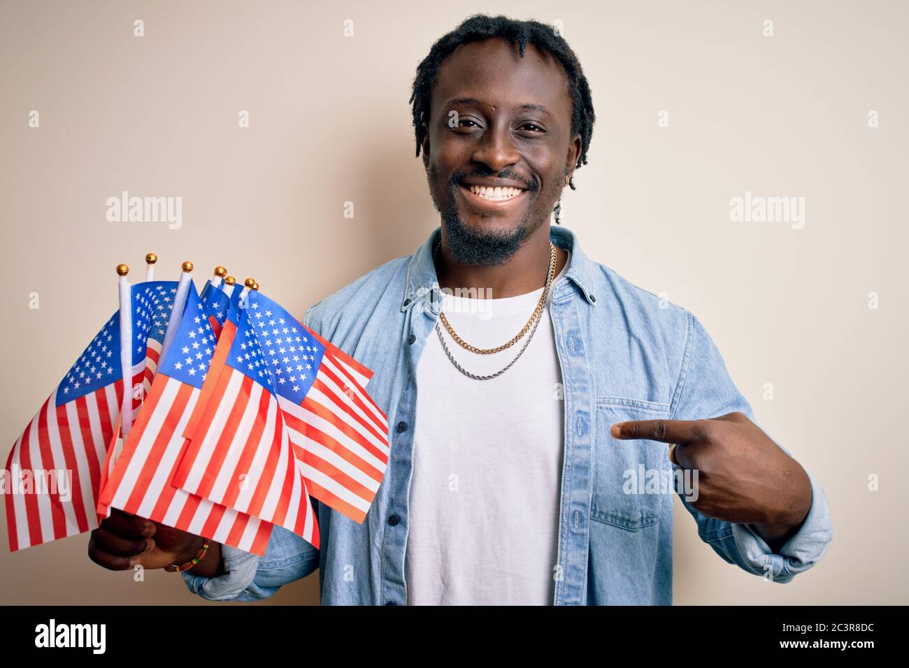 Young african american patriotic man holding united states flags over ...