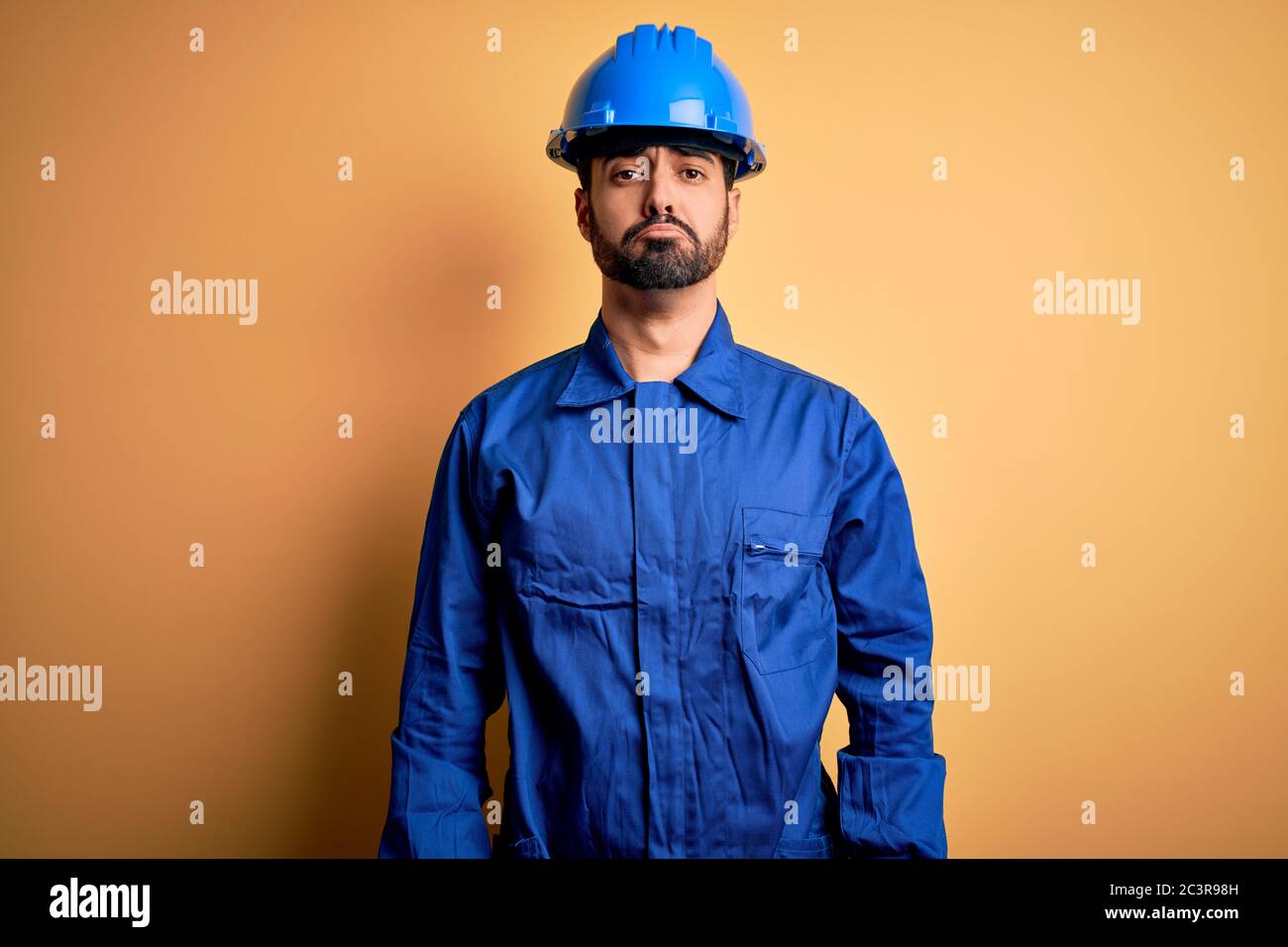 Mechanic man with beard wearing blue uniform and safety helmet over ...