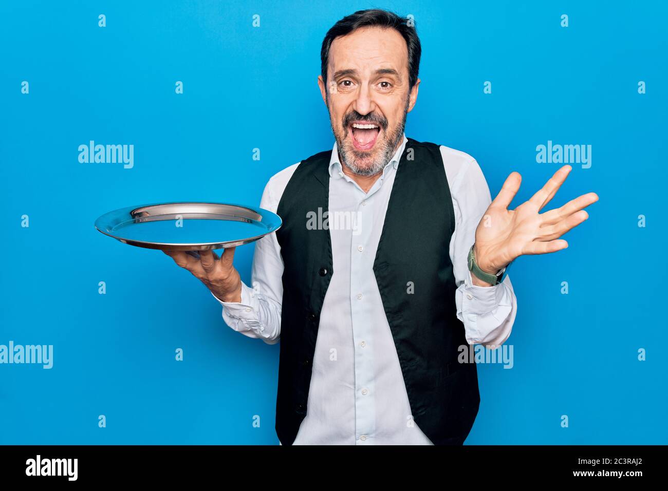 Waitressing Man Middle age handsome waitress man holding tray standing over isolated ...