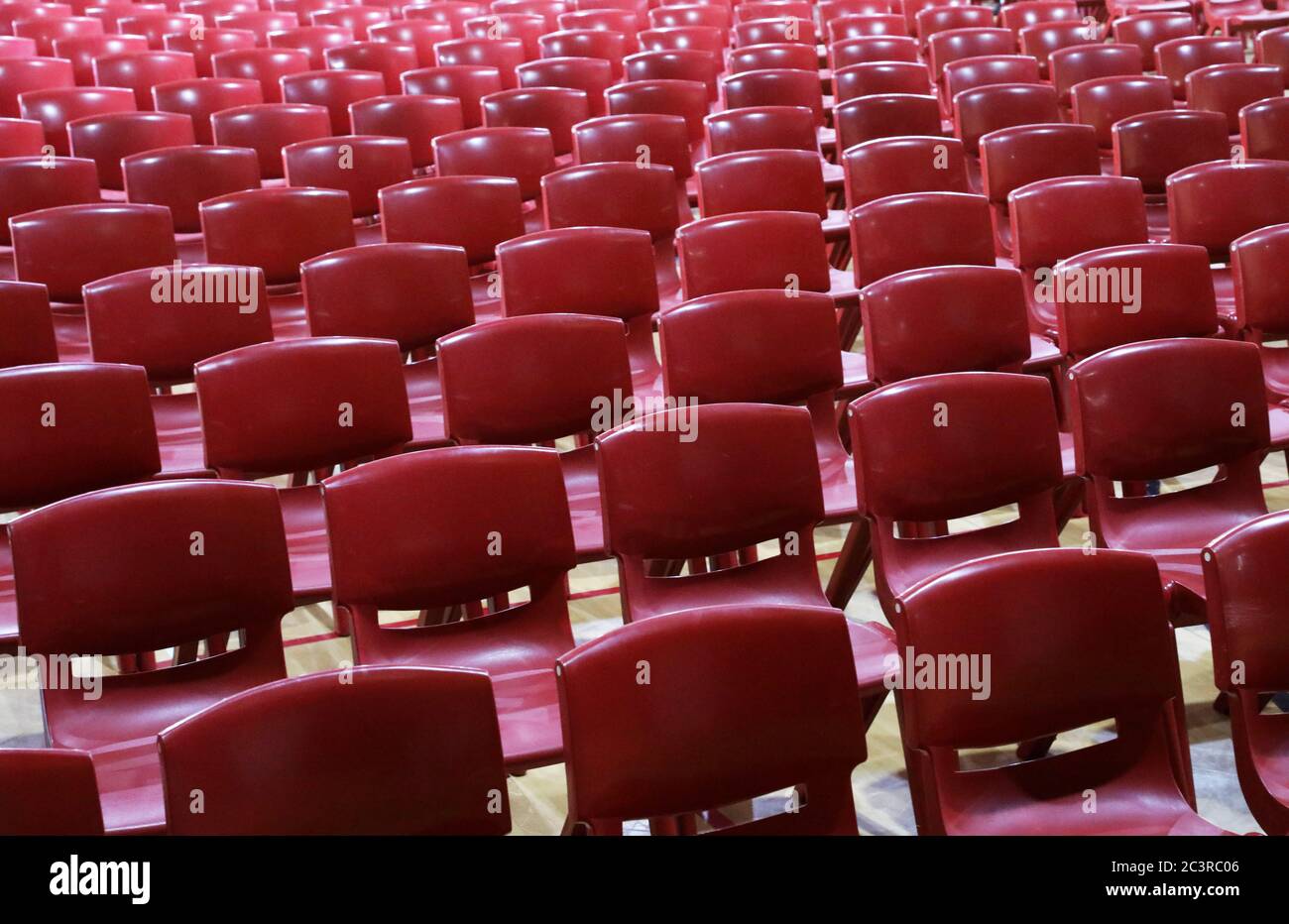Masses of red molded mass produced plastic school style chairs lined up