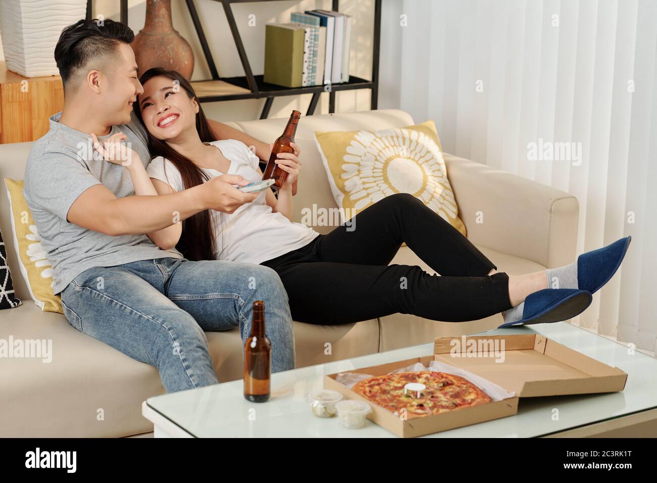 Young Vietnamese couple in love drinking beer and eating pizza when  relaxing at home on Friday evening Stock Photo - Alamy