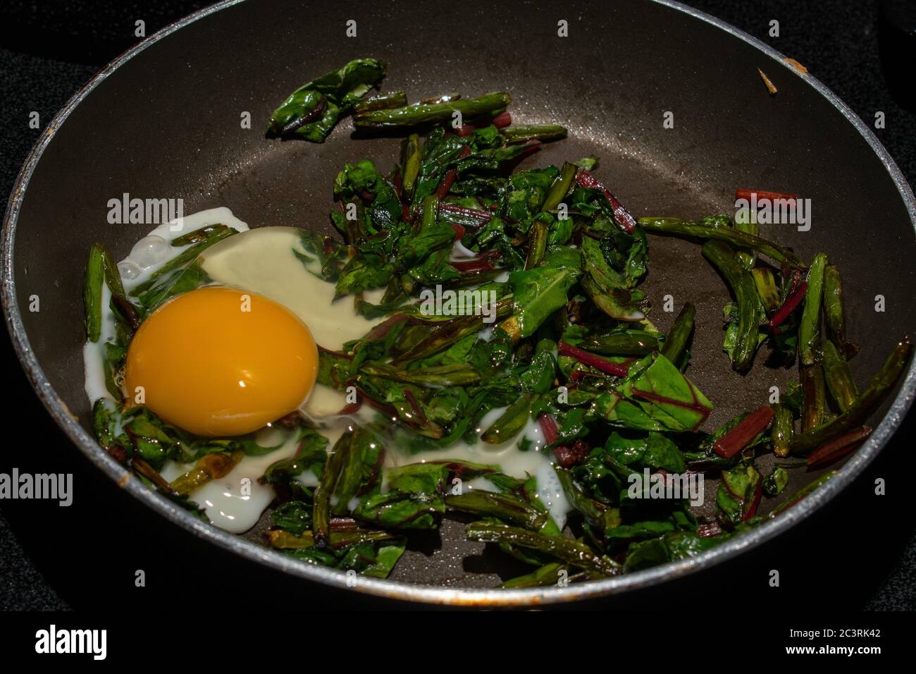 Egg added to sautéed garlic scape and swiss chard to create a healthy
