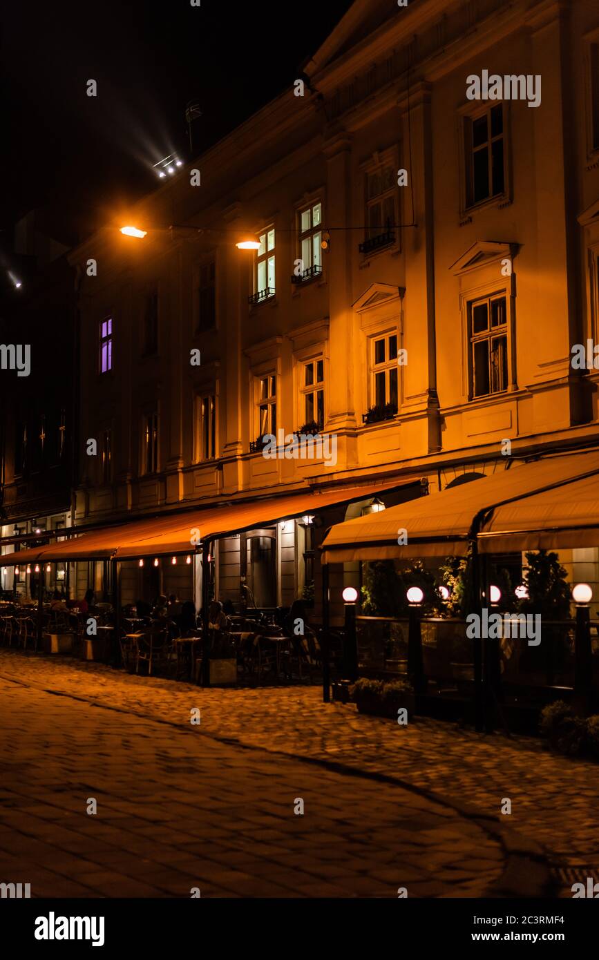 dark street and silhouette of people sitting in cafe with terrace Stock Photo