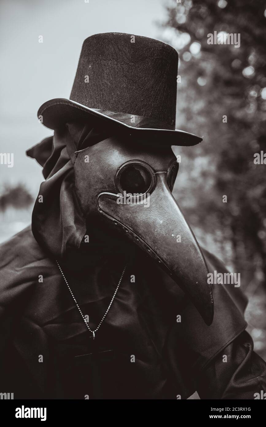 Plague doctor with a cane and a classic dark garb with a cross Stock Photo