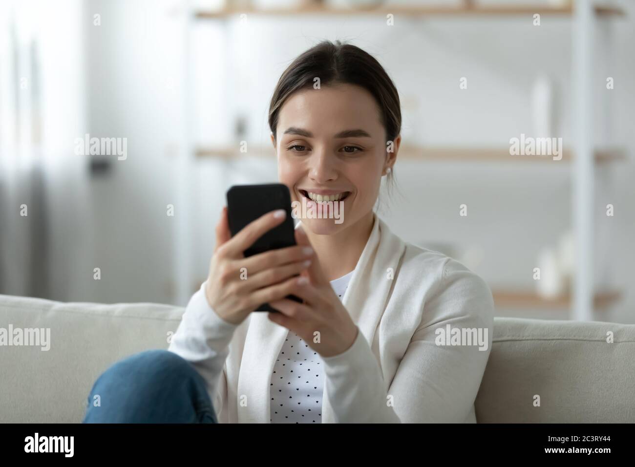 Smiling woman holding mobile phone dialing number, makes videocall Stock Photo